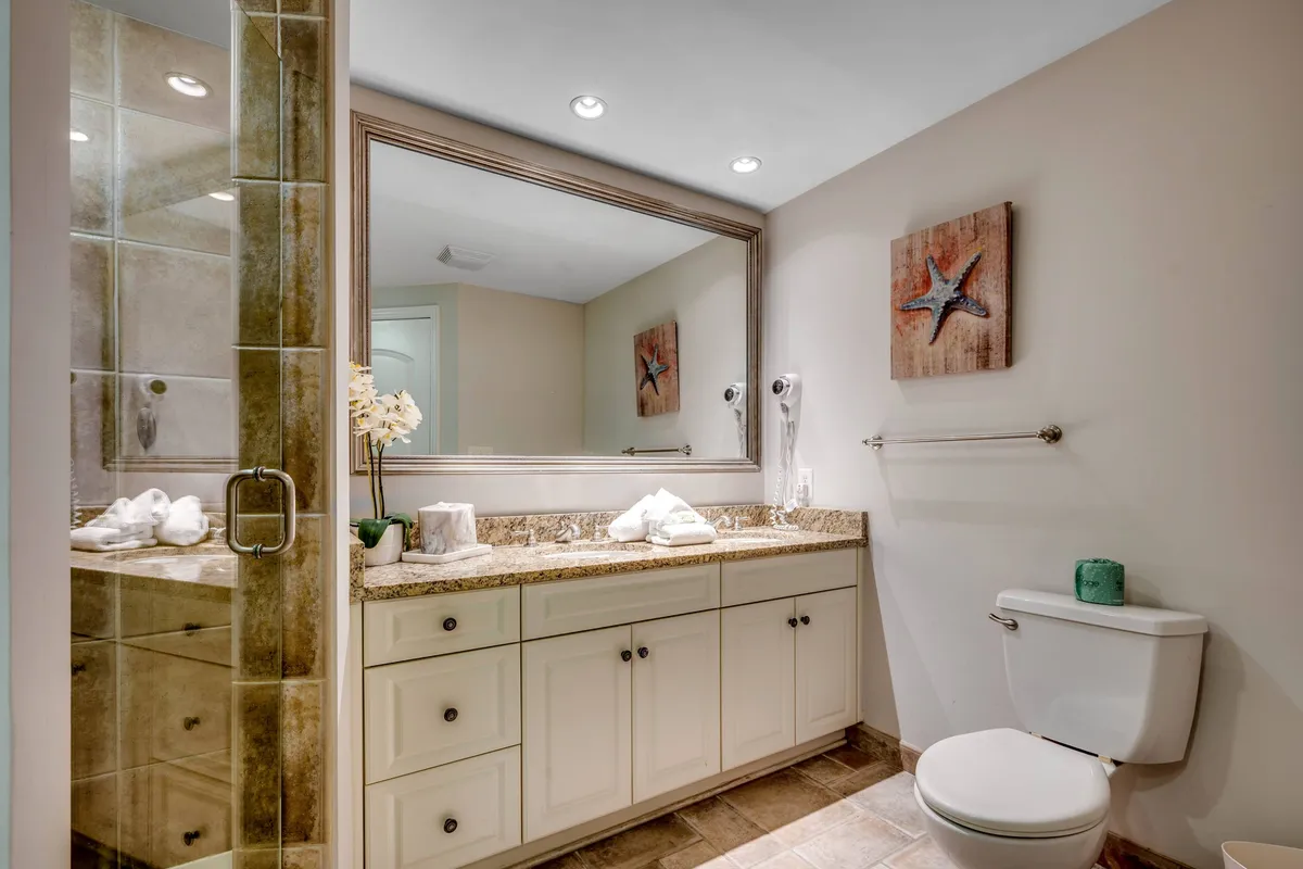 A serene interior spa-like bathroom with a granite countertop, large mirror, starfish-themed artwork, and fresh white towels. The mood is tranquil and inviting, suggesting a space for relaxation and self-care.