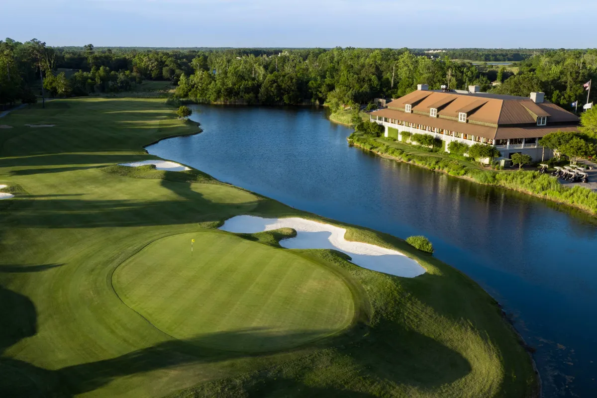 A sprawling golf course with lush green fairways, a tranquil lake reflecting the sky, and a welcoming clubhouse in the background. The scene captures the relaxed elegance of the club environment and the natural beauty of the setting, inviting guests to enjoy both recreation and leisure.