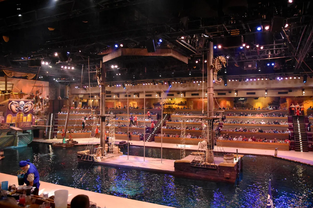 A unique interior setting featuring a stage set with water, audience seating, and immersive themed backdrops, evoking a sense of family entertainment and memorable experiences.