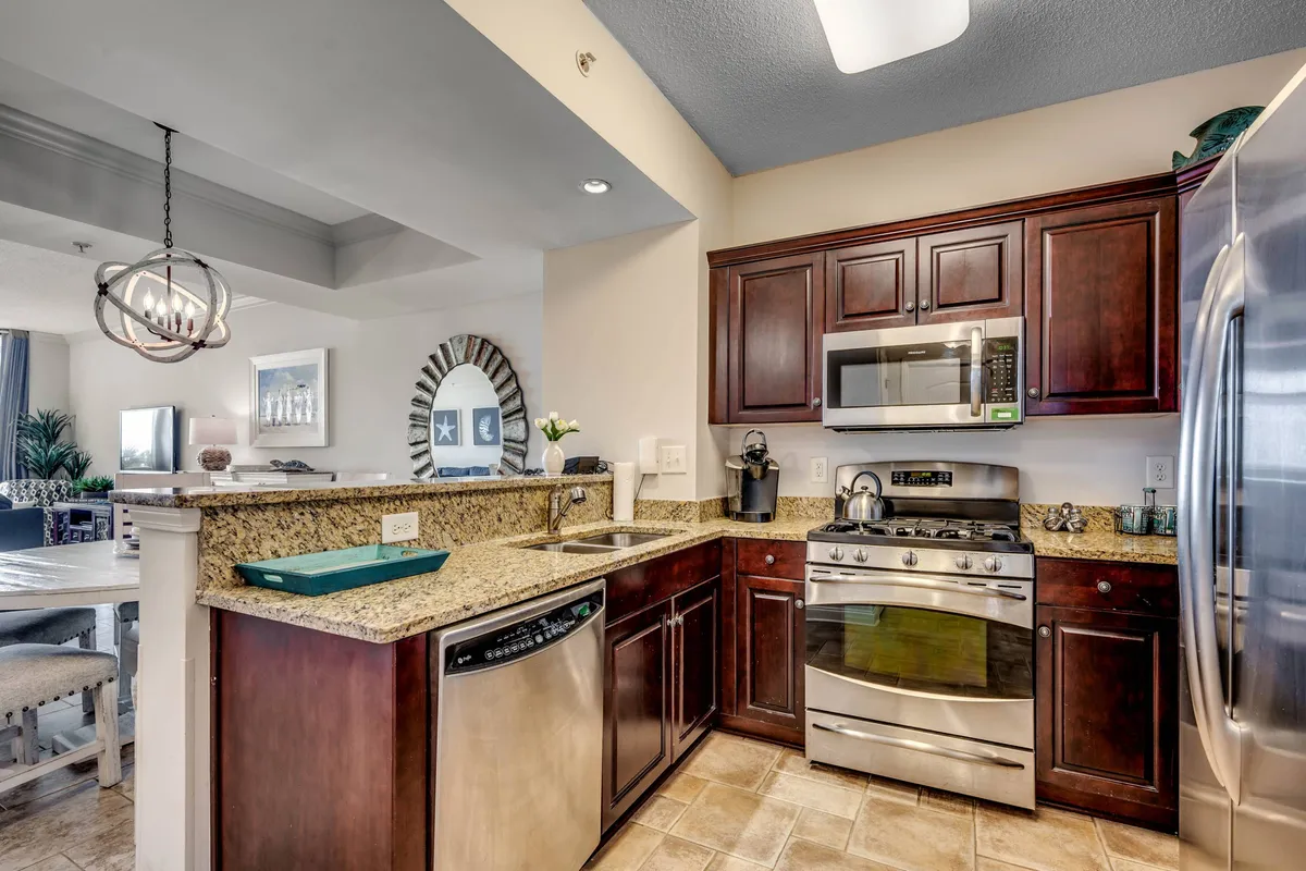 Another perspective of the kitchen, highlighting the granite countertop and stainless steel appliances. The decorative mirror and stylish details add a personal, homey touch, underscoring the warmth and sociability of the space.