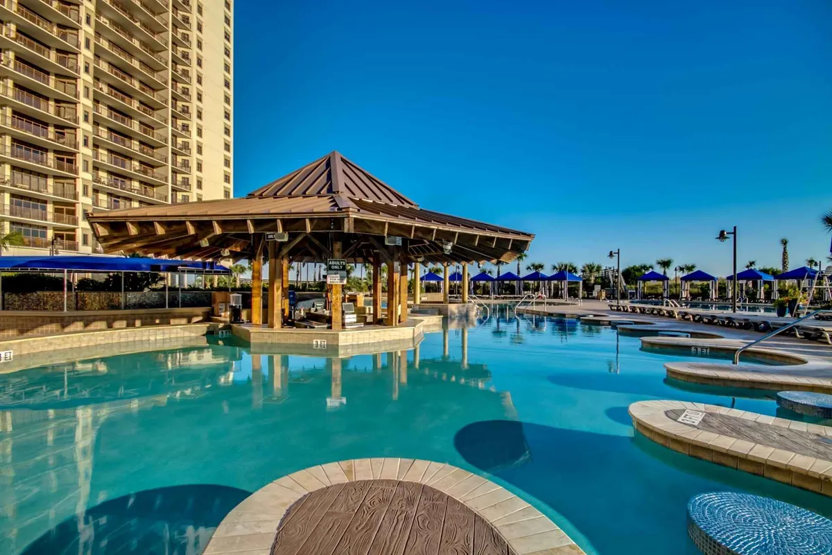 An inviting resort pool area bordered by cabanas and lounge chairs, set under a bright sky. The scene has a lively yet relaxing mood, suggesting possibilities for sunbathing, socializing, or unwinding by the water.